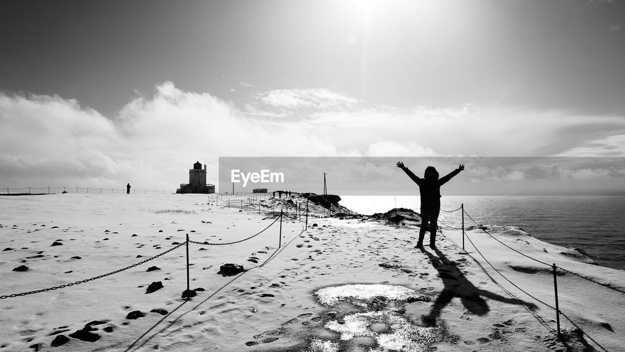REAR VIEW OF PERSON STANDING ON SHORE