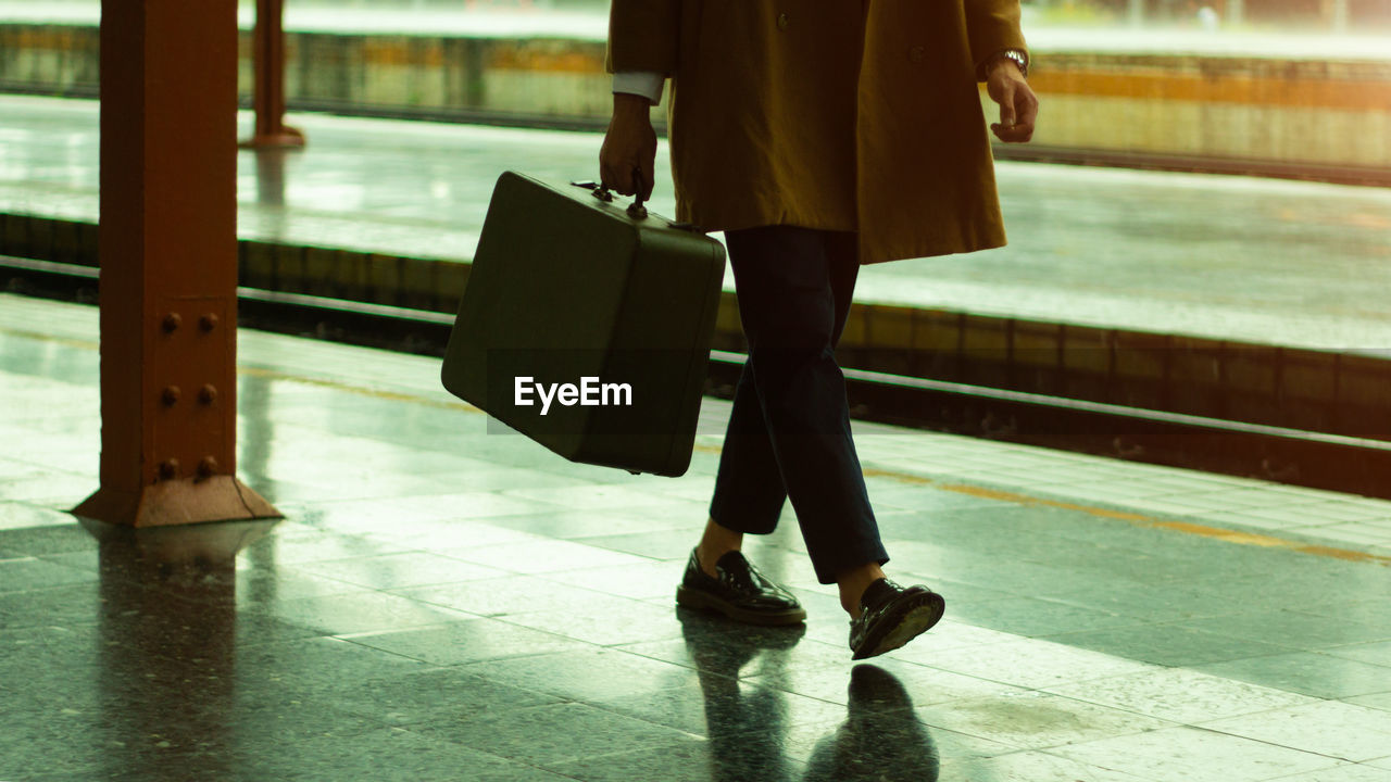 Man wear coat, carry bag at the train station.