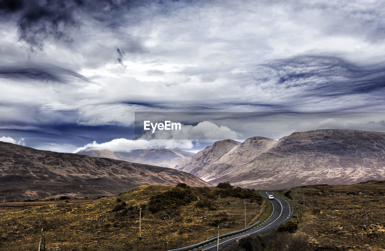 ROAD BY MOUNTAINS AGAINST SKY