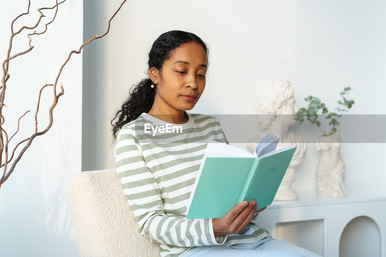 African-american woman peacefully reading book in spare time. digital detox. slow living lifestyle