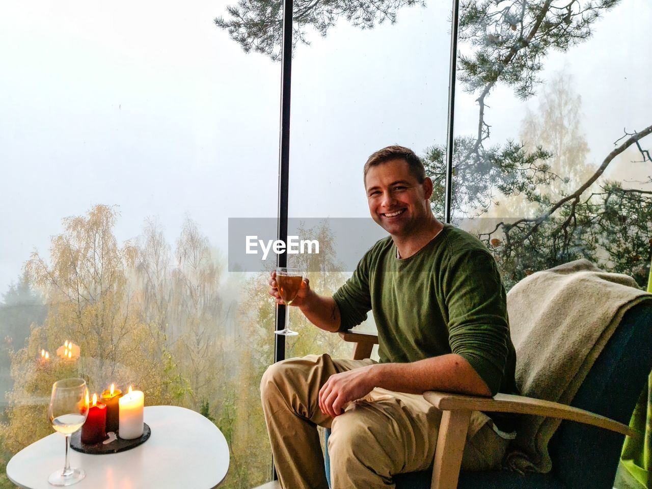 Man sitting in a forest house with a glass of wine