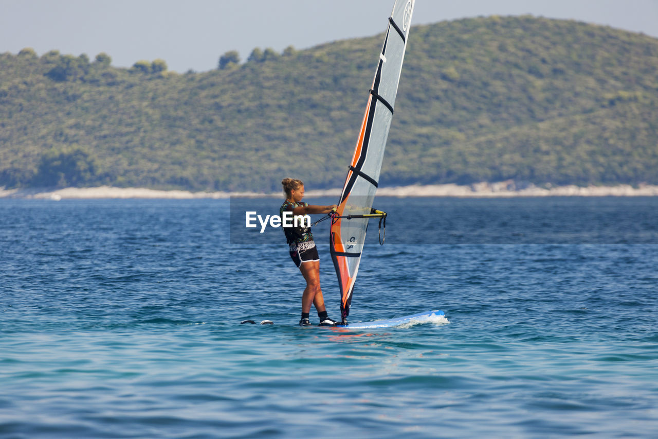 MAN IN SEA AGAINST MOUNTAIN