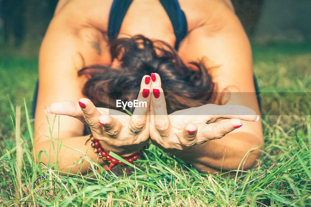 MIDSECTION OF WOMAN LYING IN GRASS