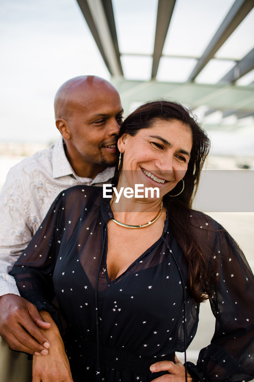Multiracial late forties couple embracing at sunset in san diego