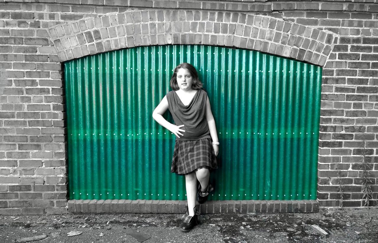 YOUNG WOMAN STANDING IN FRONT OF BUILDING