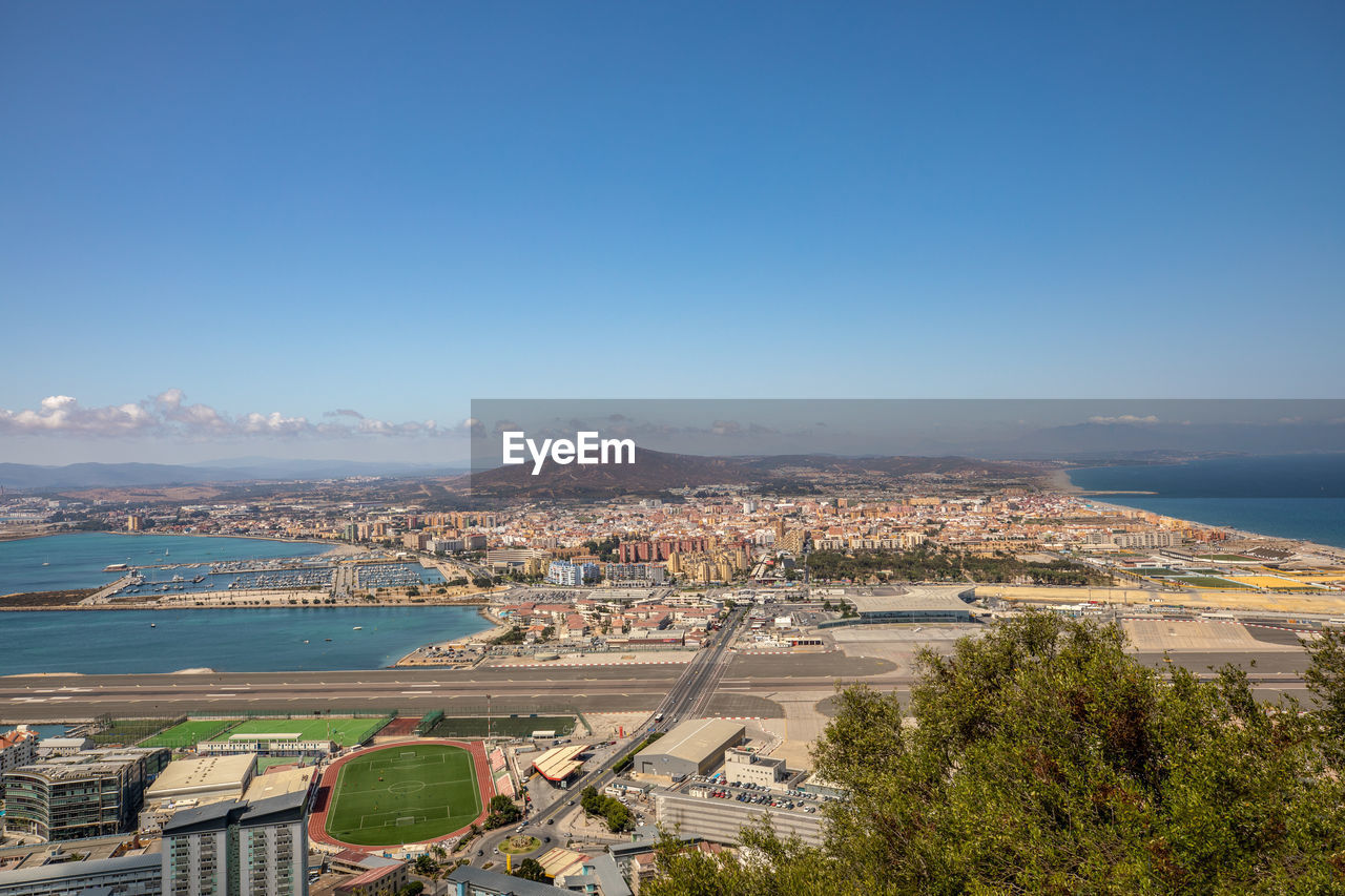 HIGH ANGLE SHOT OF TOWNSCAPE BY SEA AGAINST SKY