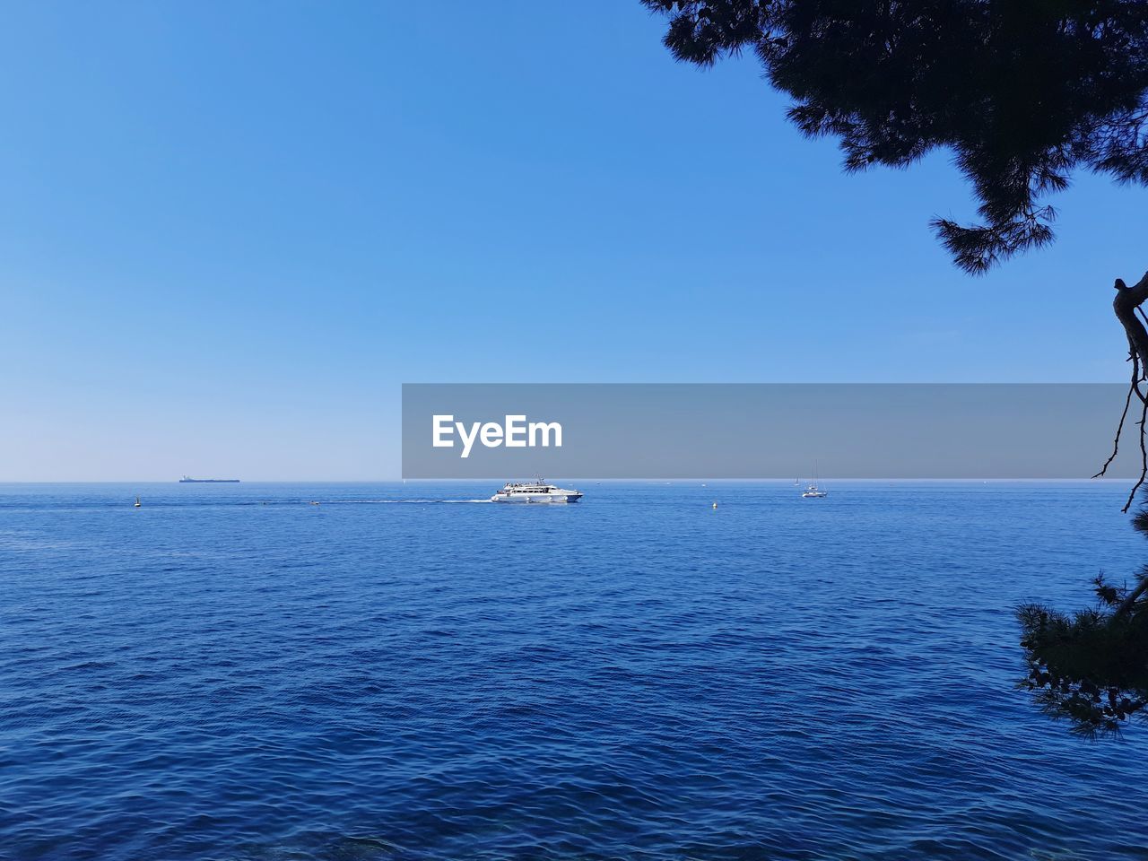 Sailboat in sea against clear blue sky