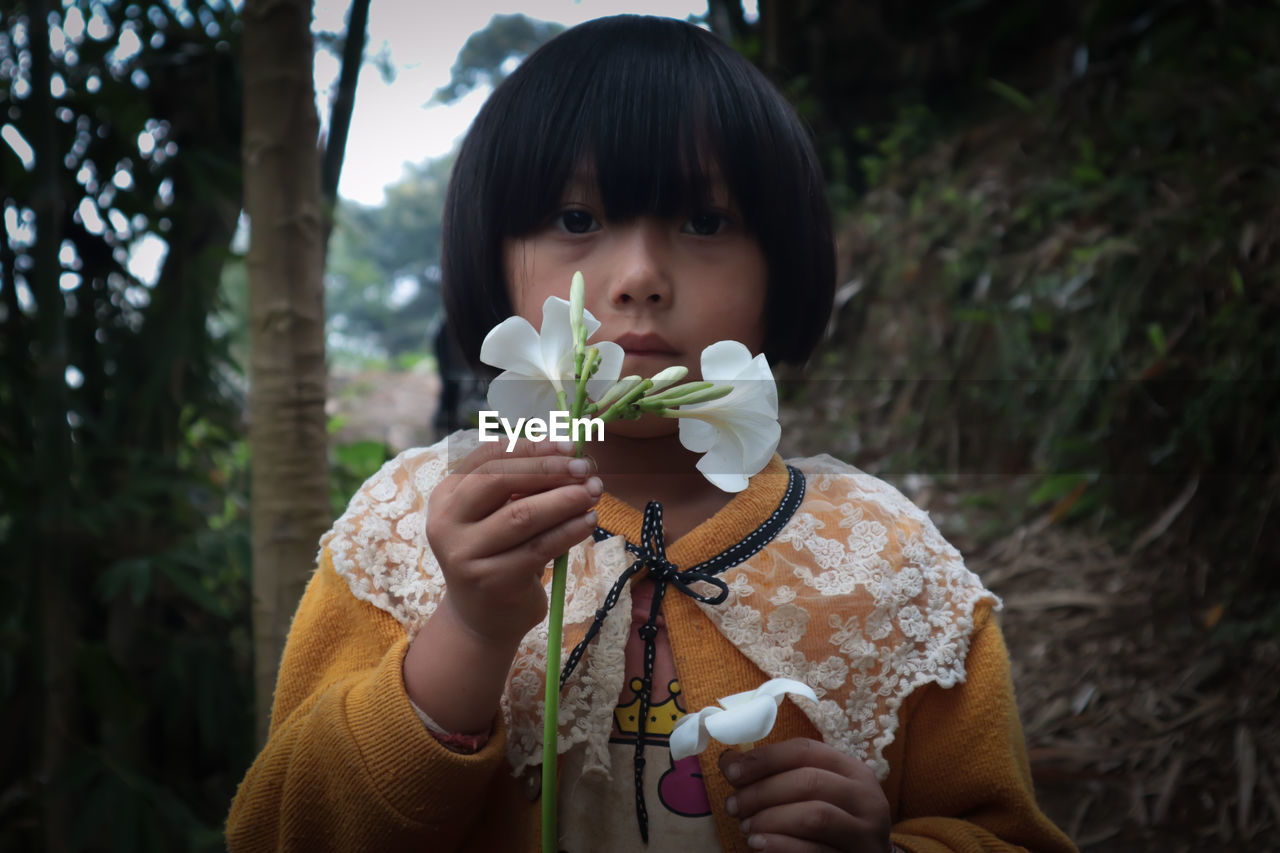 Little girl, honey skinned girl, big eyes, beautiful frangipani flowers