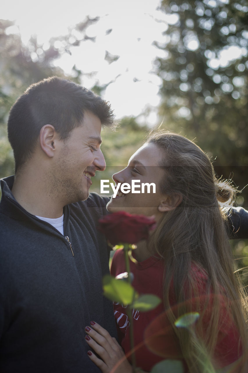 Smiling couple with rose standing outdoors