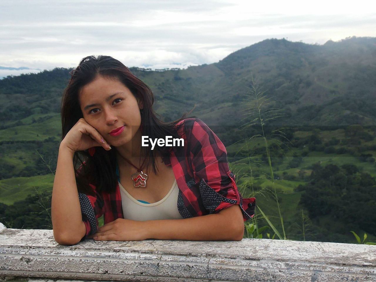 Portrait of woman leaning on railing against mountain