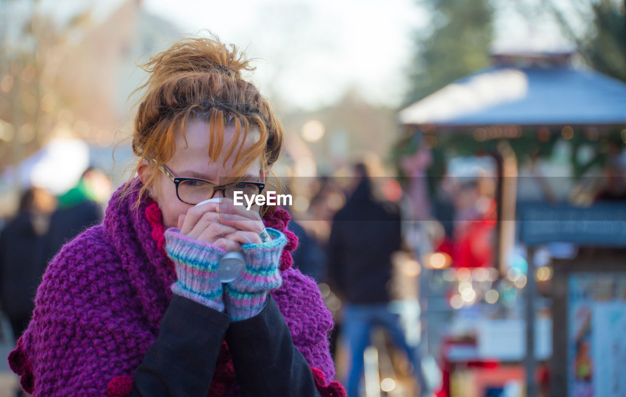 Portrait of woman drinking tea at market during winter