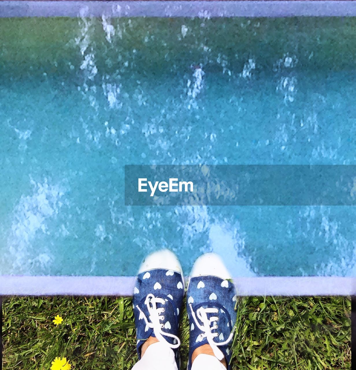 LOW SECTION OF WOMAN STANDING ON EDGE OF POND