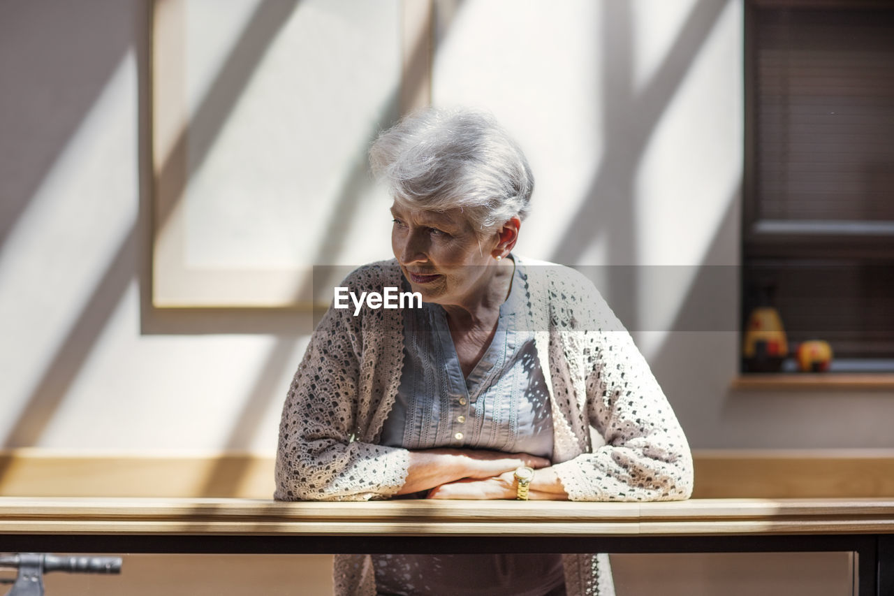 Lonely senior woman leaning on railing, looking down