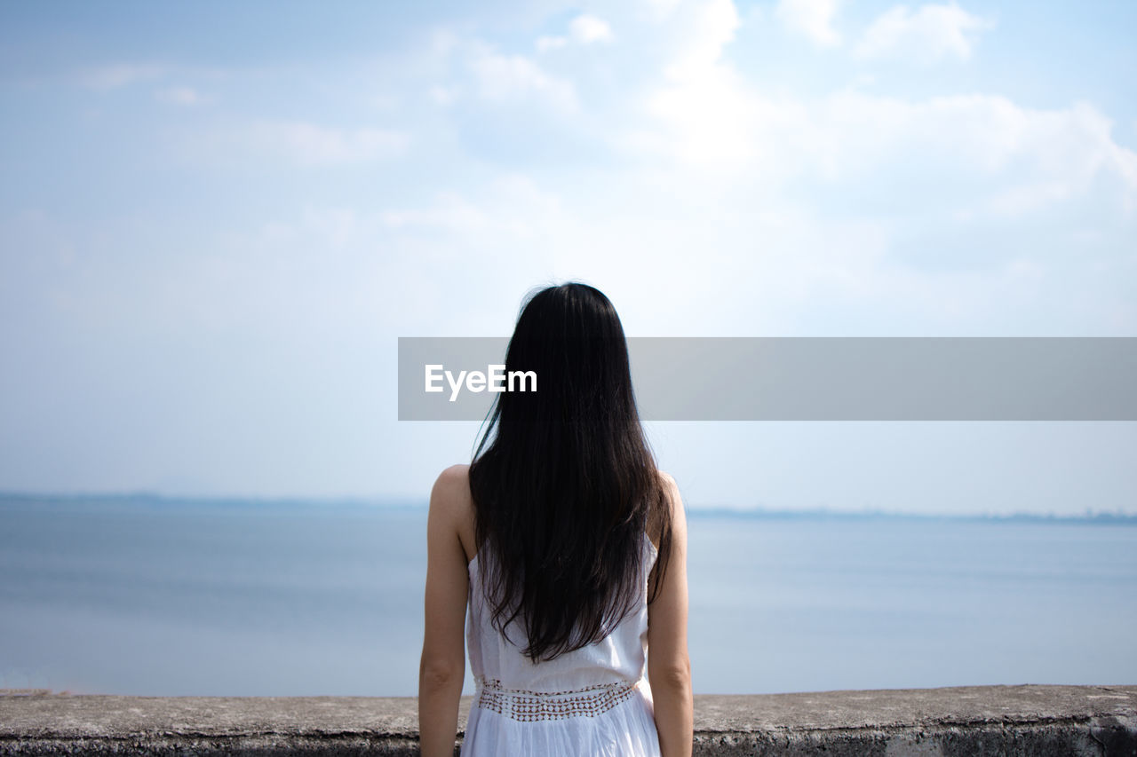 Rear view of woman looking at sea against sky