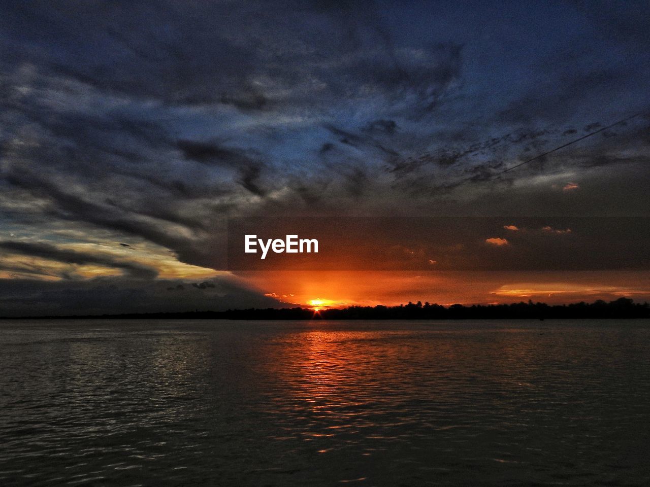 Scenic view of sea against dramatic sky during sunset