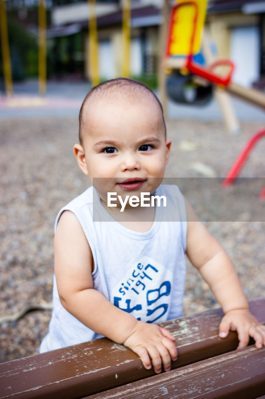 Cute pretty little baby baby on children playground
