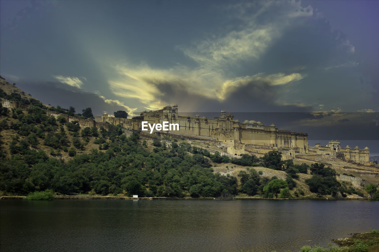 Scenic view of river by city against sky and amer fort of jaipur rajasthan 