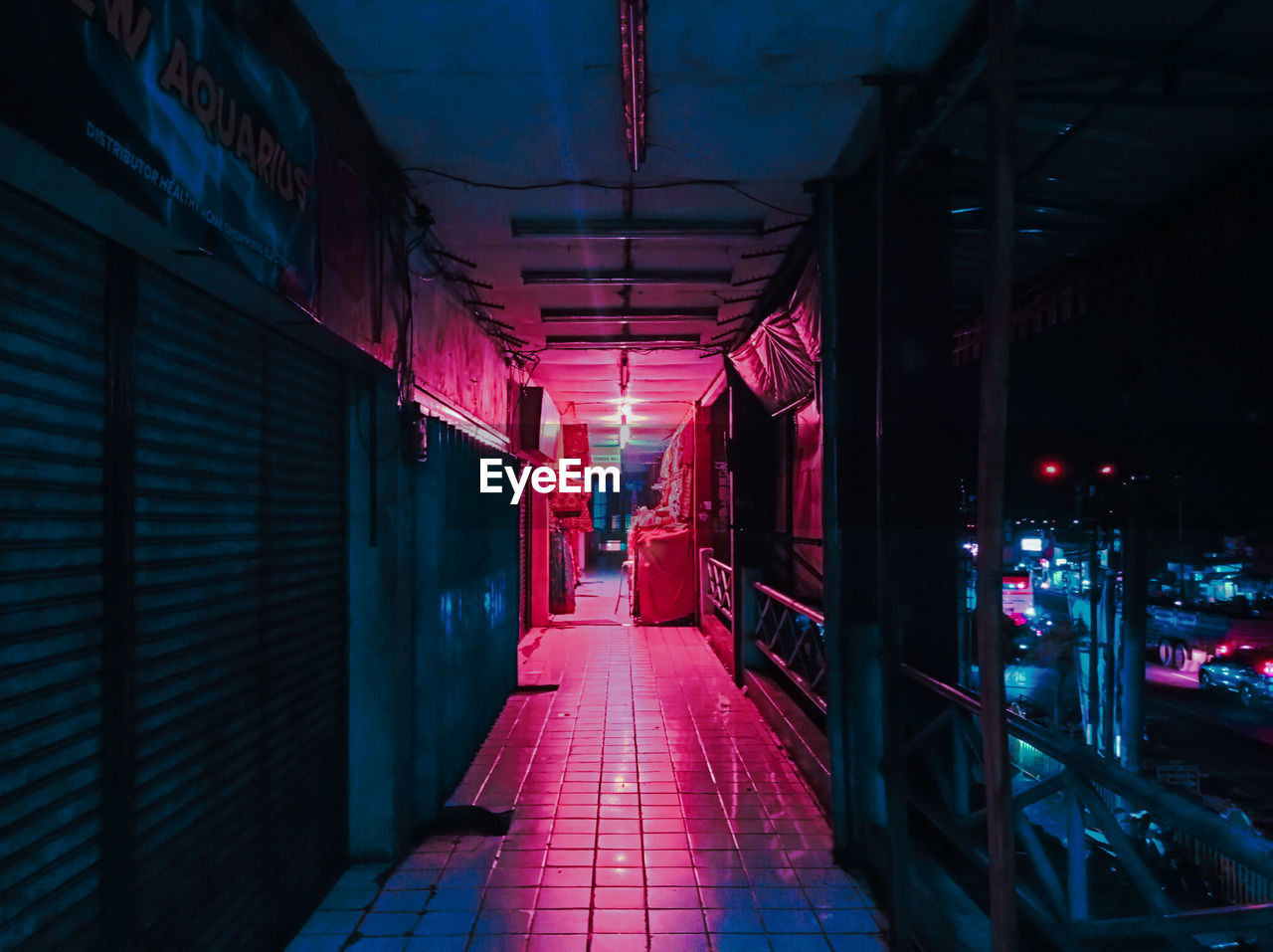 Empty corridor along buildings at night