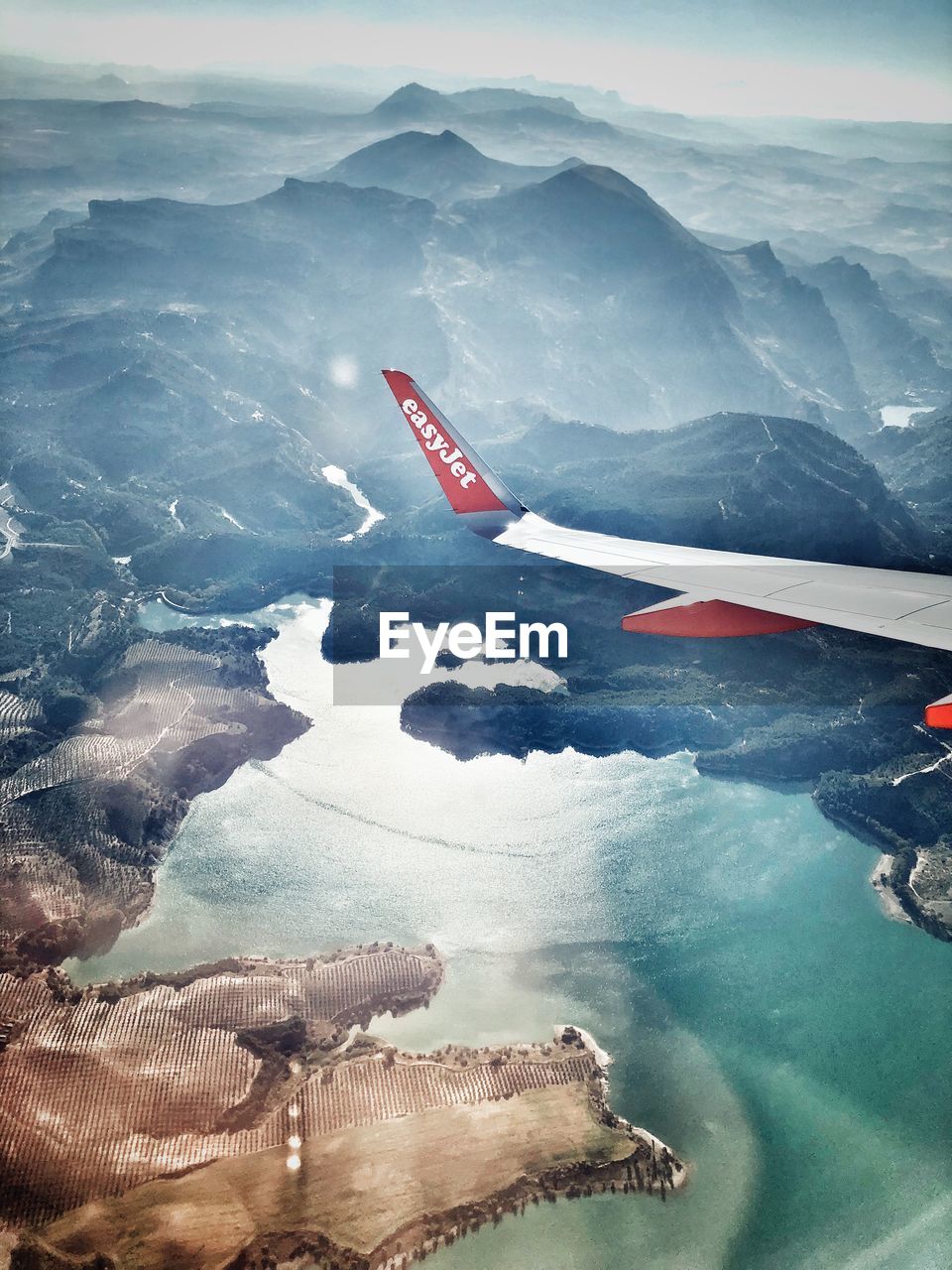 AERIAL VIEW OF AIRPLANE FLYING OVER MOUNTAINS