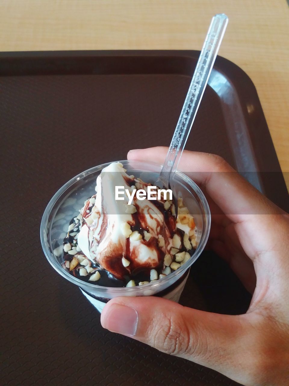 MIDSECTION OF PERSON HOLDING ICE CREAM IN GLASS CONTAINER