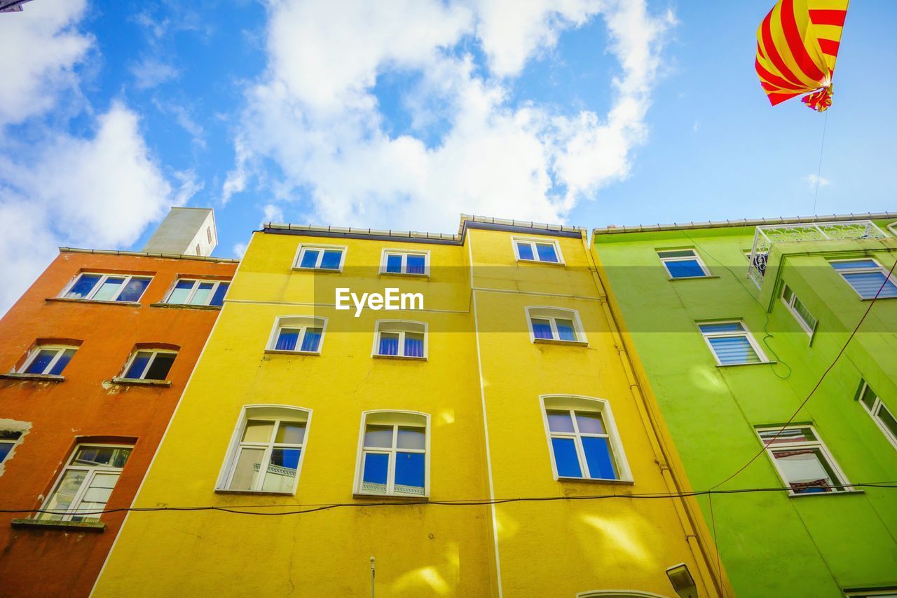 Low angle view of colorful buildings against cloudy sky in city