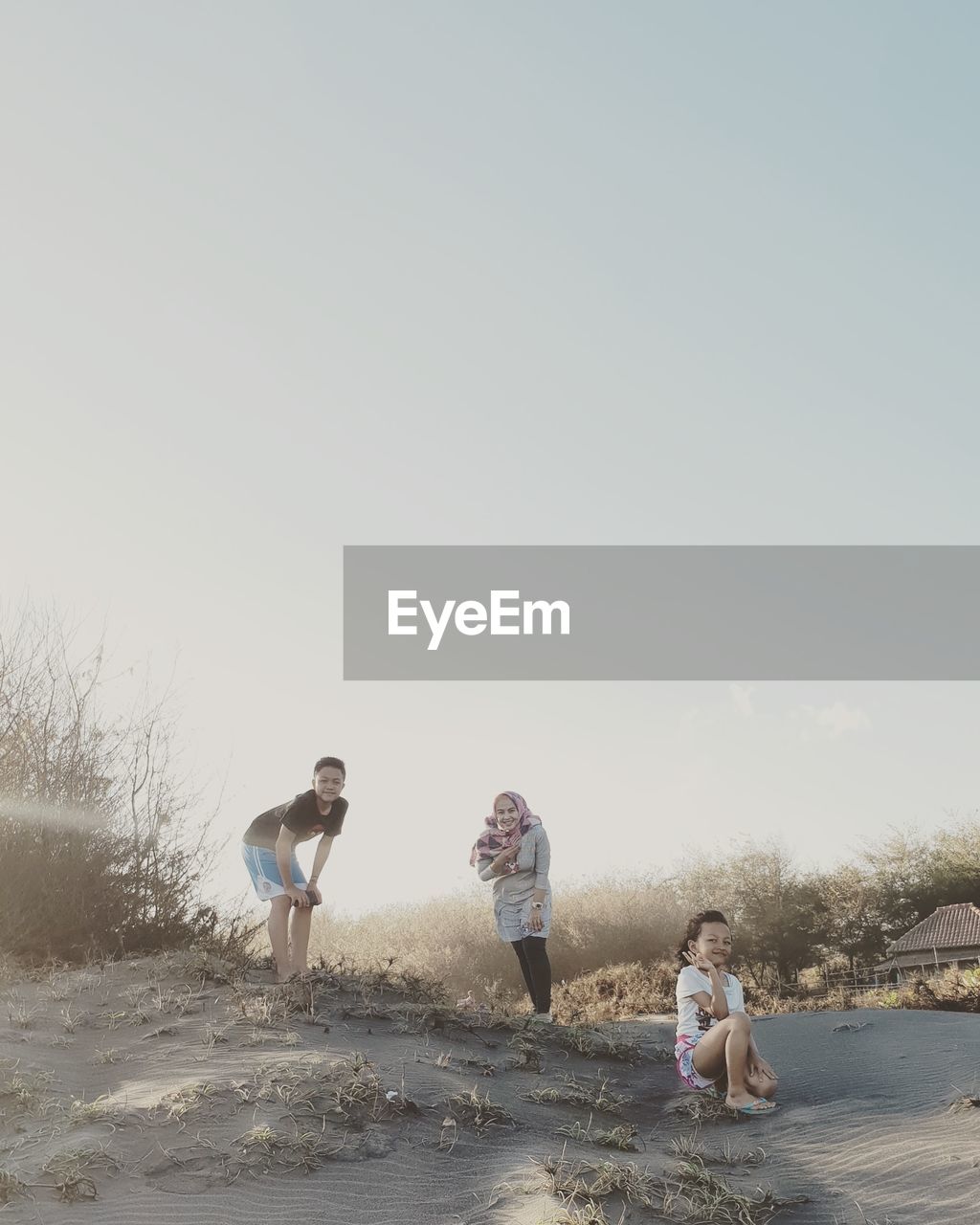 Mother standing with children at beach against clear sky