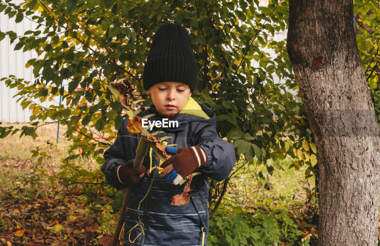 Child helps to clean up the leaves in the backyard garden. 