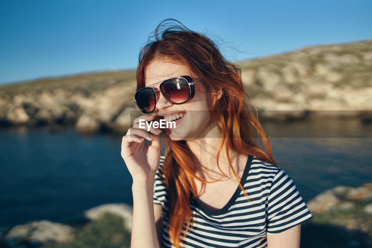 PORTRAIT OF YOUNG WOMAN WEARING SUNGLASSES