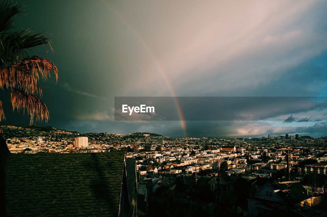 Rainbow over cityscape against sky