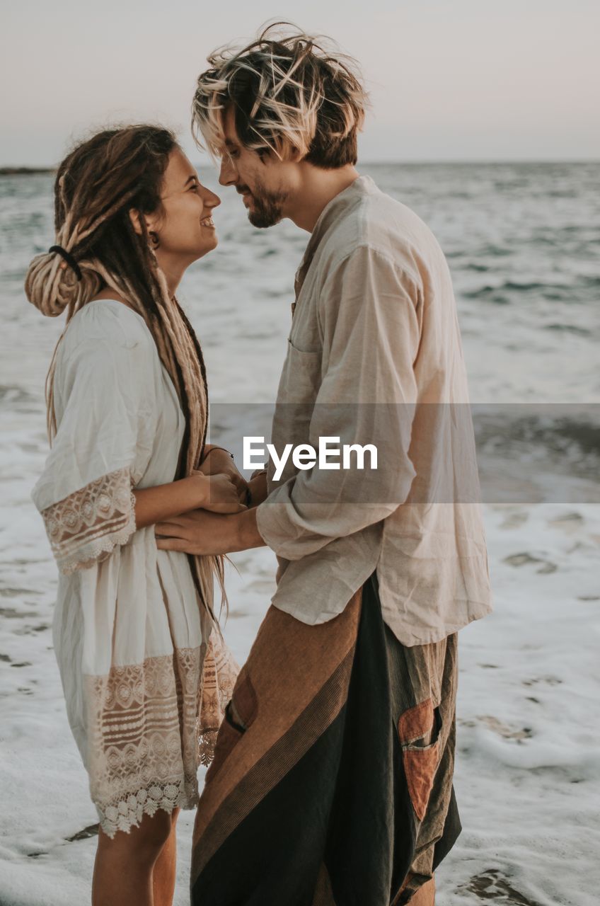 SIDE VIEW OF COUPLE STANDING IN SEA