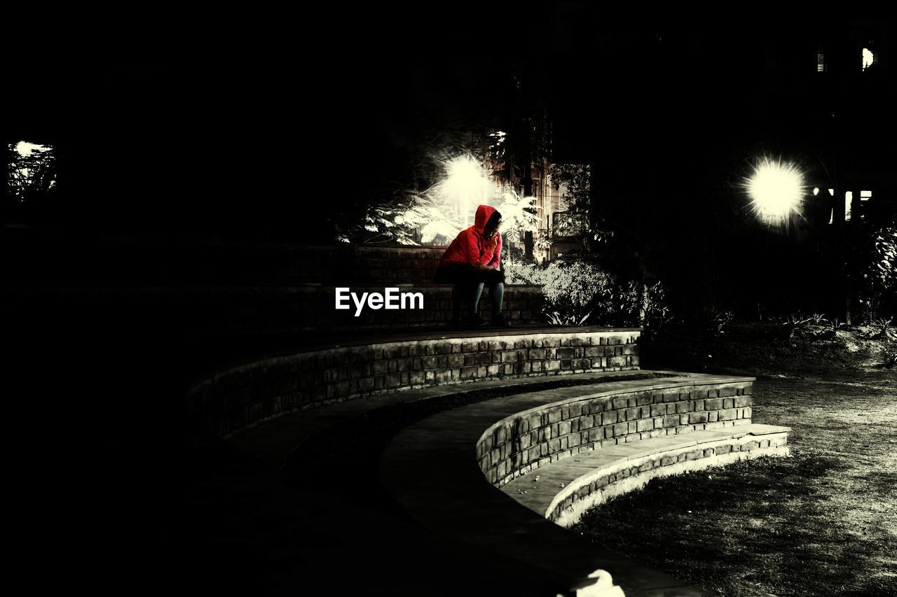 REAR VIEW OF MAN WALKING ON STEPS AT NIGHT