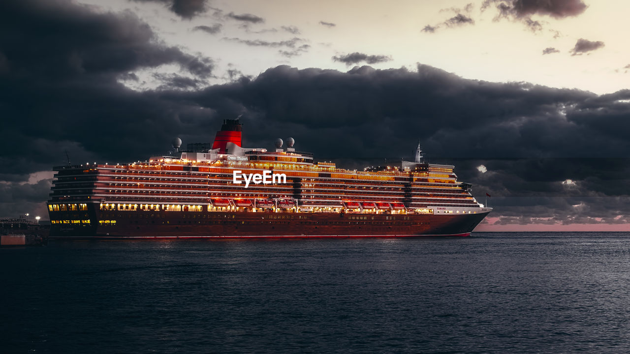 ILLUMINATED SHIP BY SEA AGAINST SKY DURING SUNSET