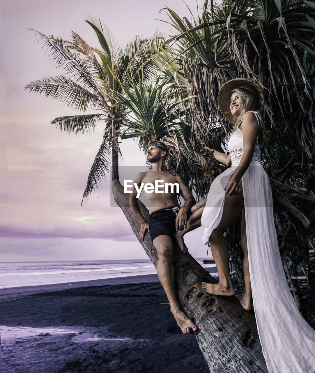 Young couple on tree trunk at beach
