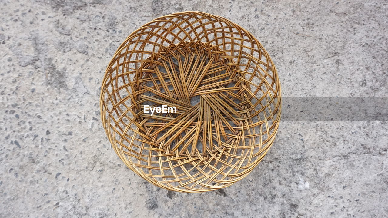 HIGH ANGLE VIEW OF WICKER BASKET ON CONCRETE