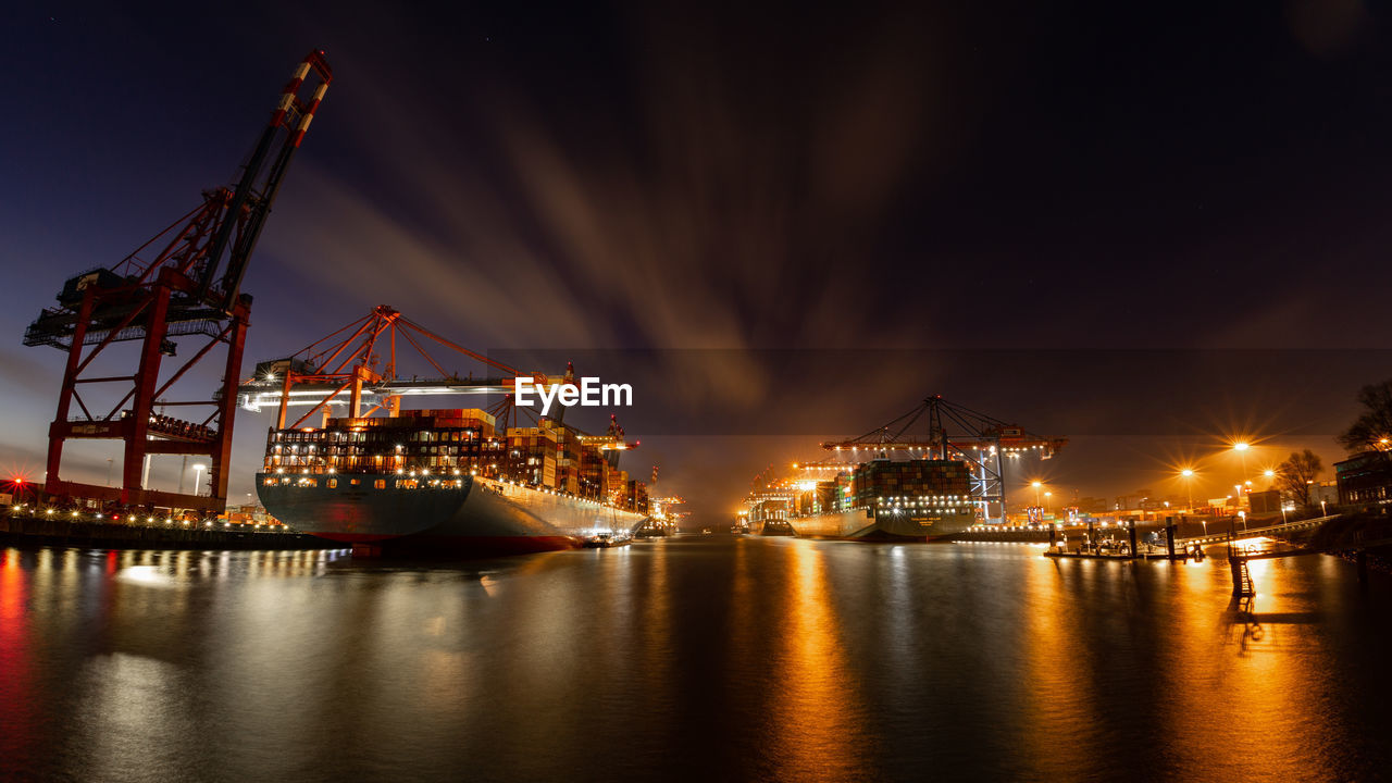 Container terminal with container ships, cranes and containers at night with beautiful clouds