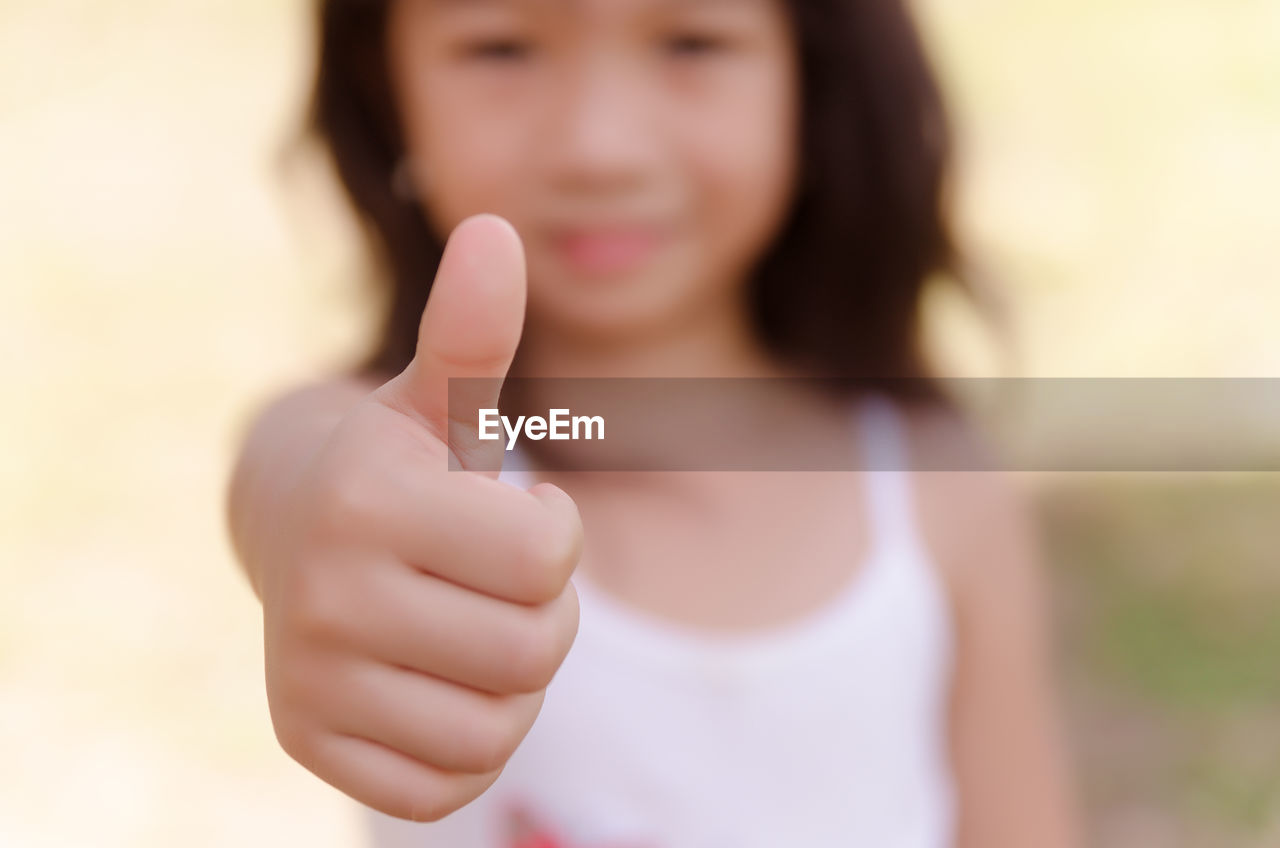 Portrait of girl gesturing thumbs up
