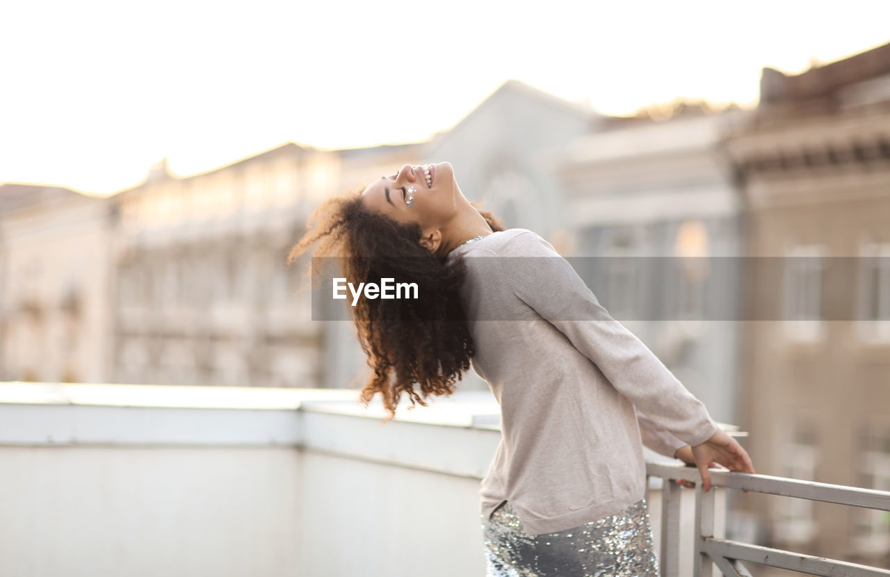 side view of young woman looking away while standing against railing