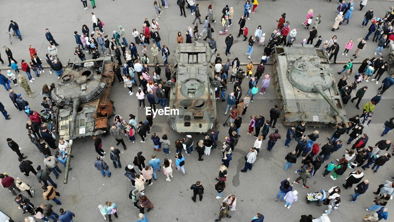 High angle view of people walking on street next to the wrecked russian fascist equipment