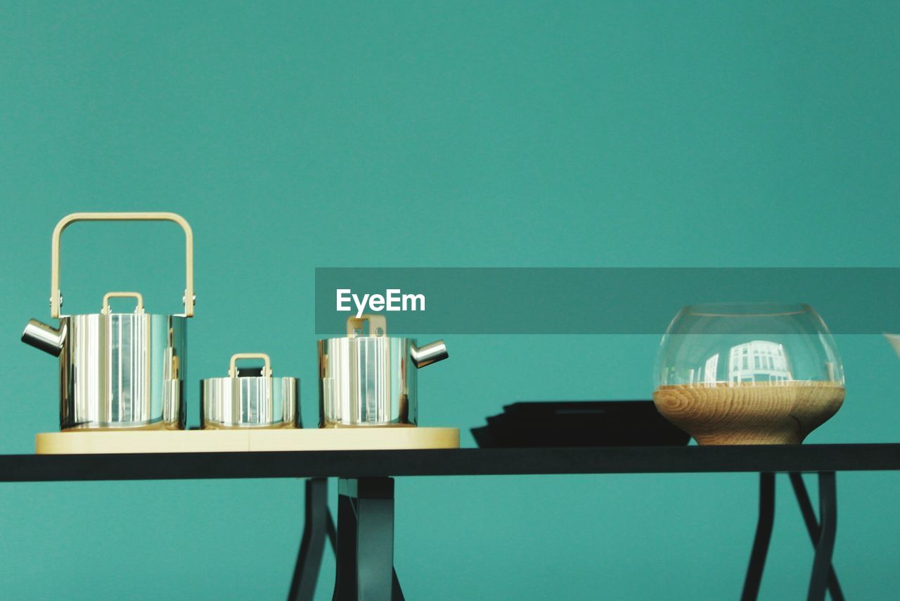 Close-up of teapots on table against blue background