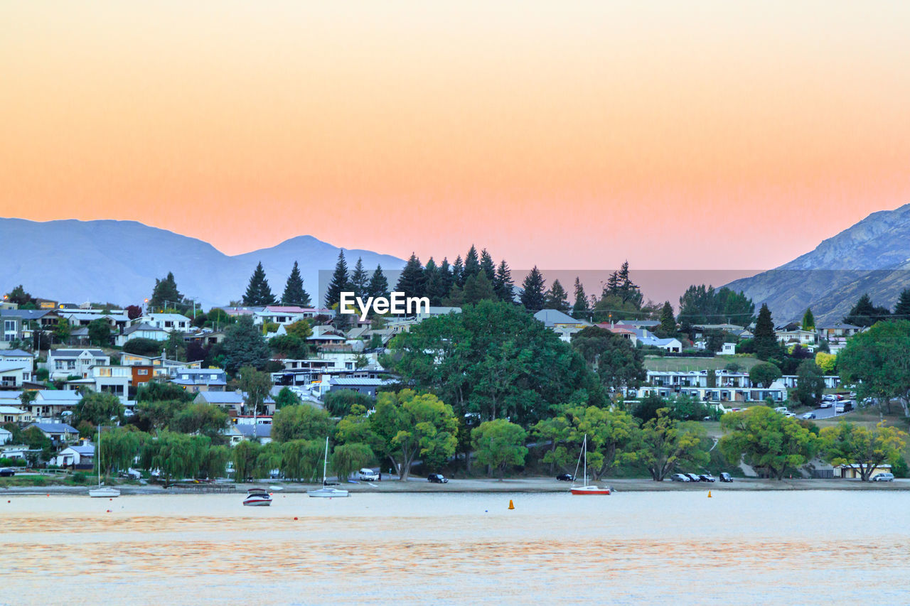 Town by sea against sky during sunset