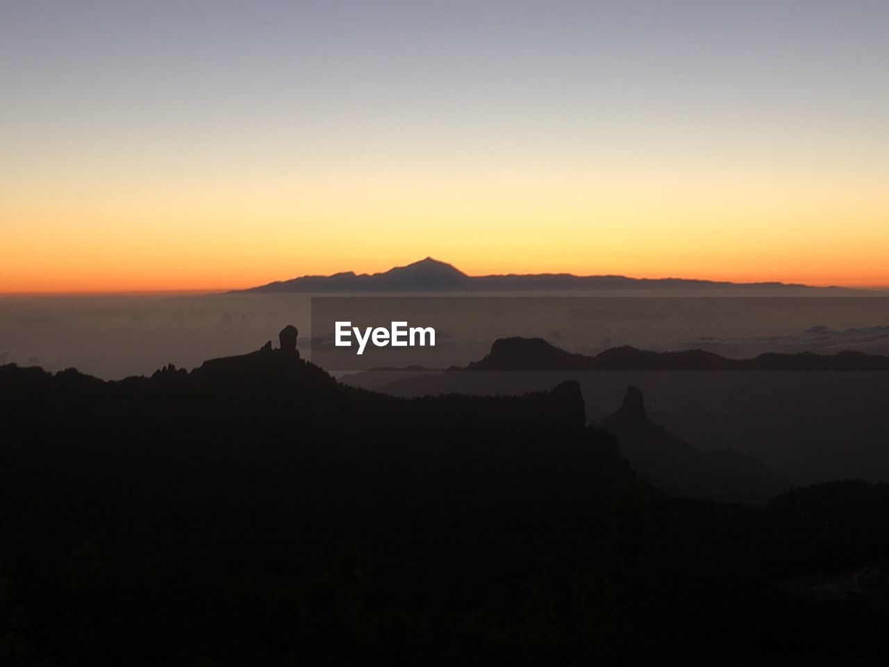 Scenic view of silhouette mountains against orange sky