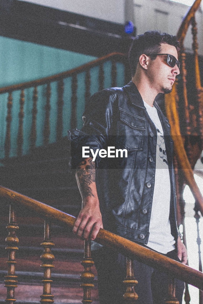 Young man wearing sunglasses standing by railing