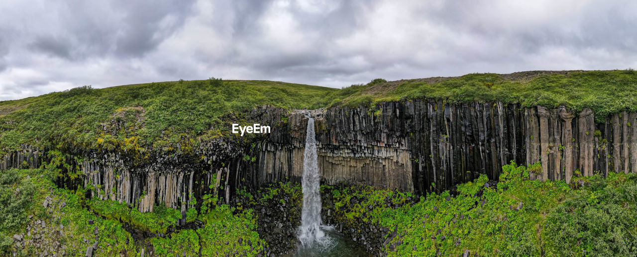 panoramic view of waterfall in forest against sky