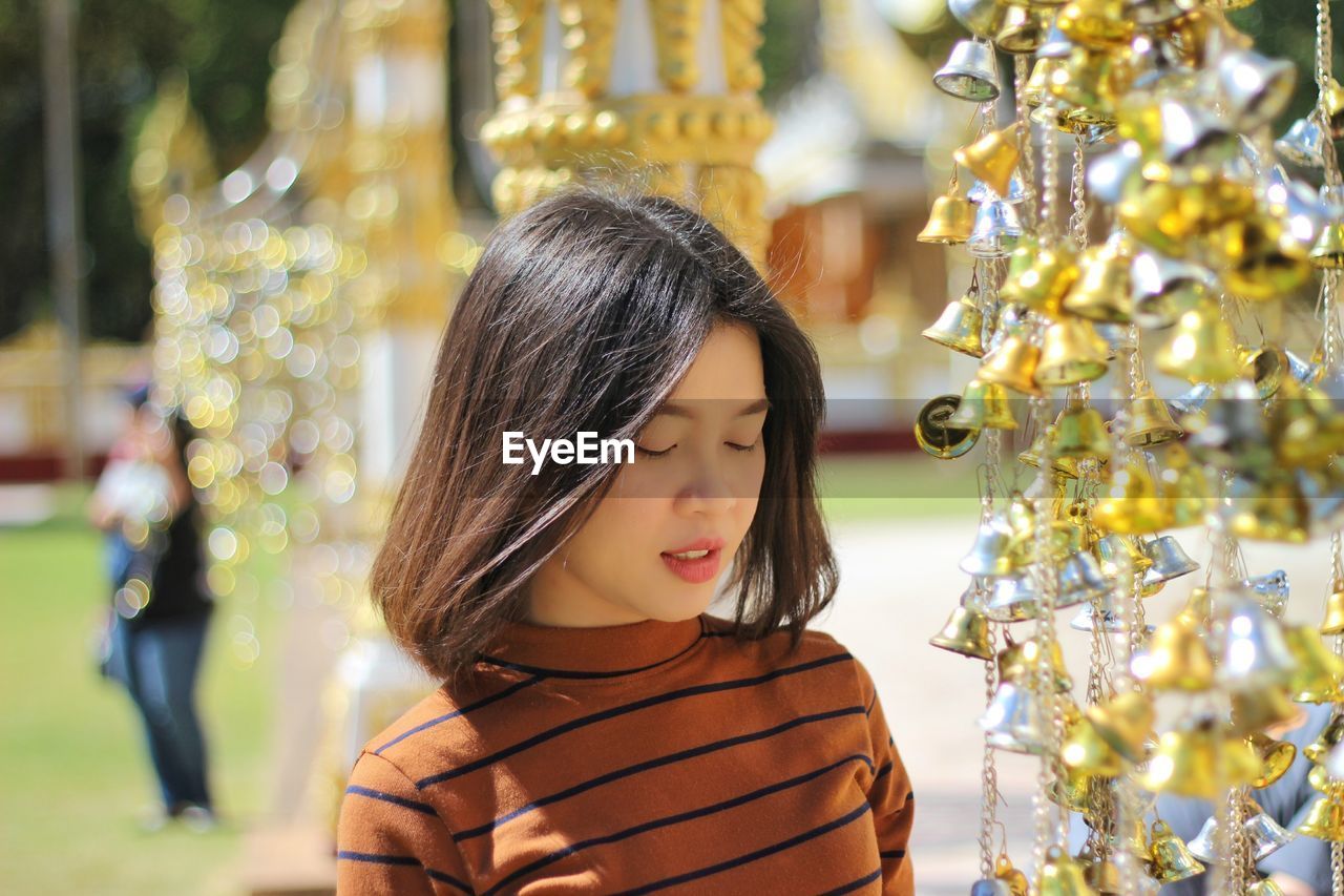 Close-up of woman with eyes closed standing by christmas decorations during sunny day