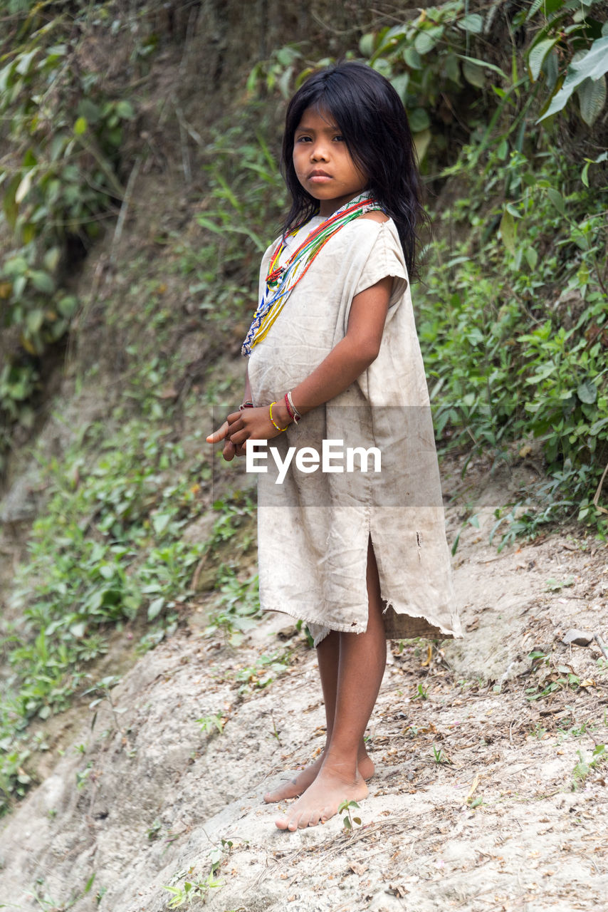 PORTRAIT OF YOUNG WOMAN STANDING ON GROUND