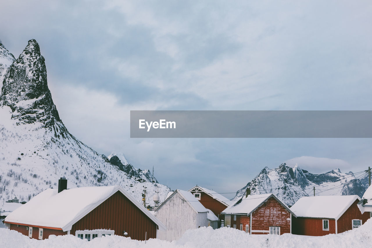 Houses by snow covered mountains against sky