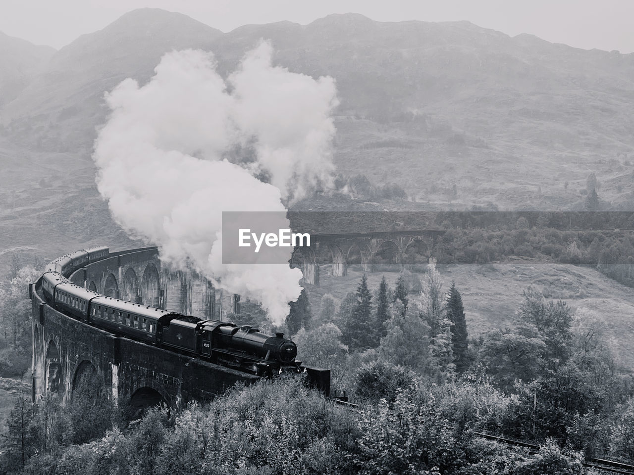 Scenic view of mountains and a steam train on a viaduct 