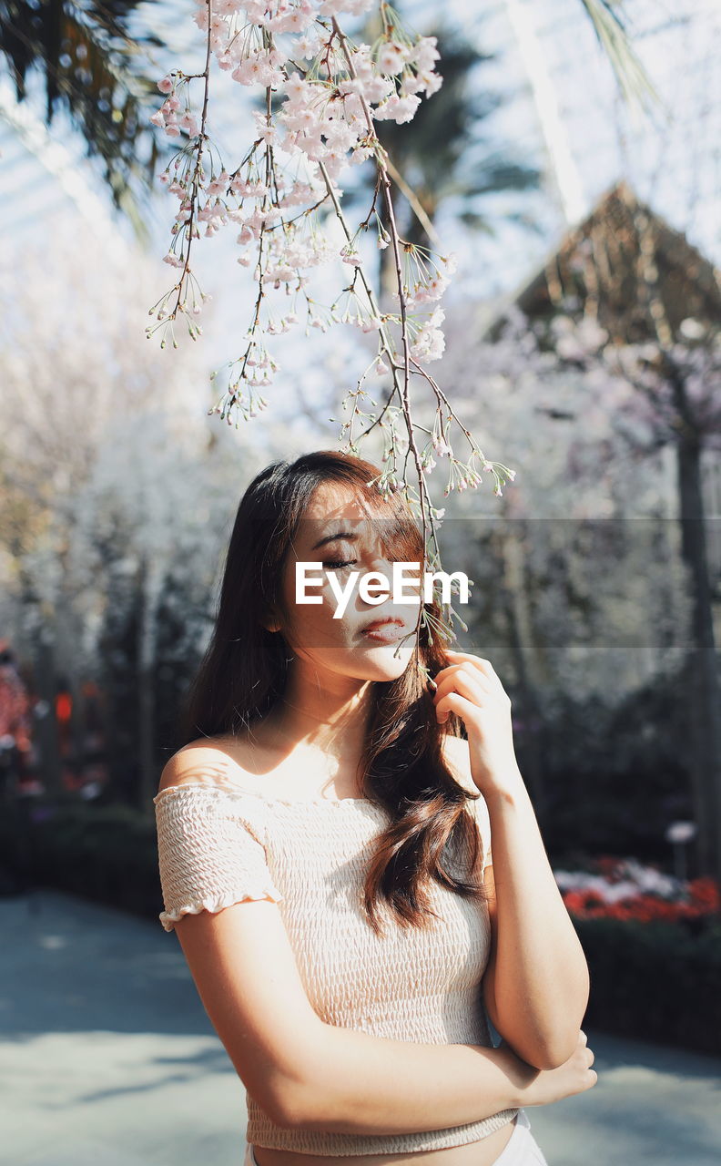 Young woman holding flower buds while standing at park