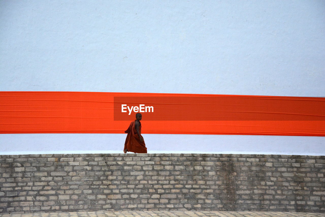 WOMAN WALKING ON RED BRICK WALL