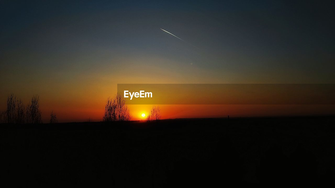 SCENIC VIEW OF SILHOUETTE FIELD AGAINST ORANGE SKY